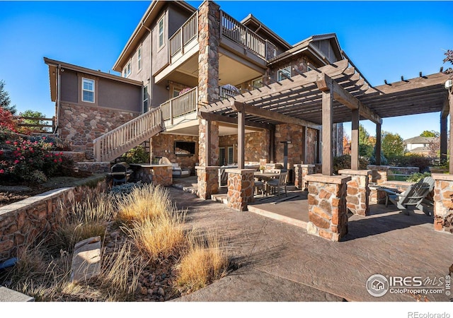 view of patio featuring a fireplace, a pergola, and a balcony