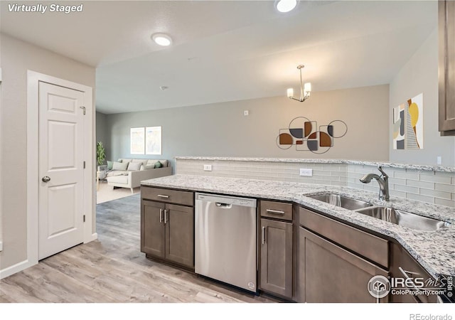 kitchen featuring sink, backsplash, decorative light fixtures, stainless steel dishwasher, and light stone countertops