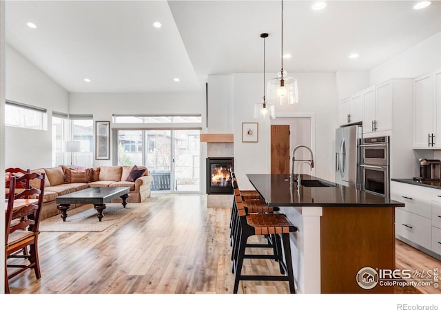 kitchen featuring a center island with sink, decorative light fixtures, sink, appliances with stainless steel finishes, and a kitchen bar