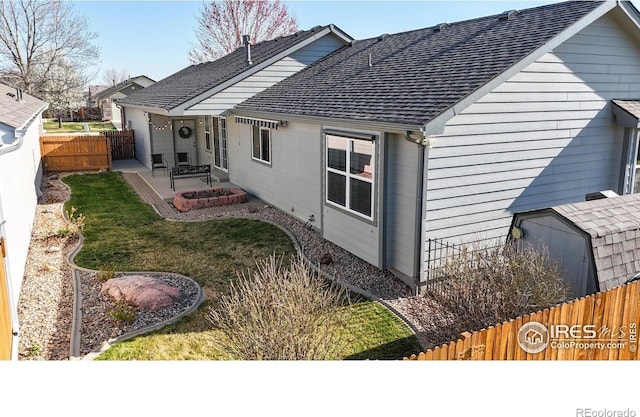 rear view of house with a patio area, a fenced backyard, an outdoor structure, and a shingled roof