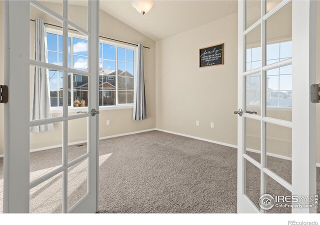 empty room with carpet, french doors, lofted ceiling, and baseboards