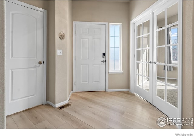 entrance foyer featuring light wood-style floors, french doors, visible vents, and baseboards