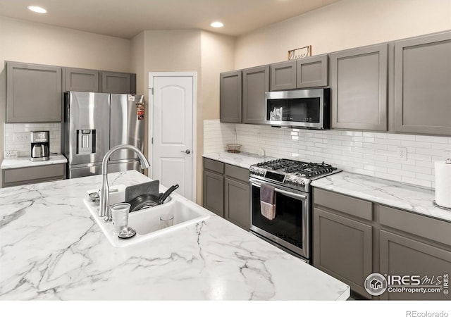 kitchen with recessed lighting, gray cabinets, decorative backsplash, appliances with stainless steel finishes, and a sink