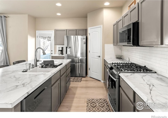 kitchen featuring decorative backsplash, appliances with stainless steel finishes, gray cabinets, and a sink