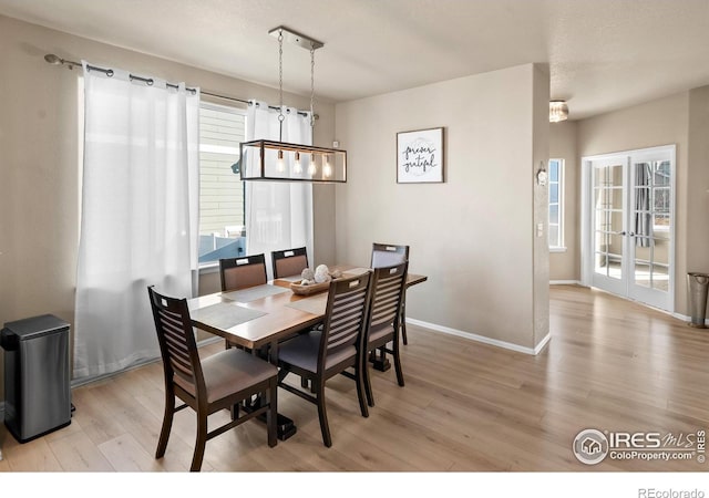 dining space with light wood finished floors, baseboards, and french doors