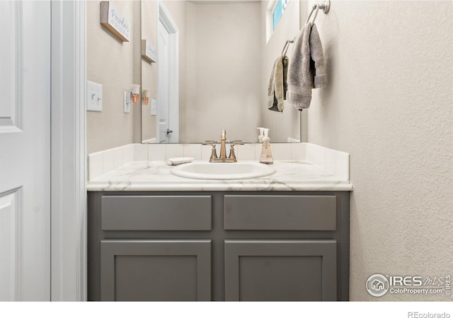 bathroom featuring a textured wall and vanity