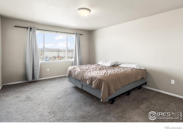 bedroom featuring dark carpet and baseboards