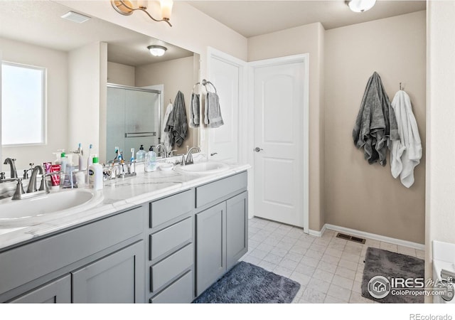 full bath featuring double vanity, a shower stall, visible vents, and a sink