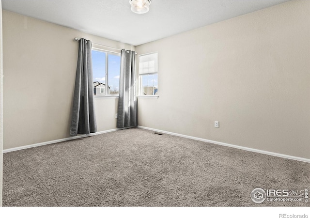 carpeted spare room featuring visible vents and baseboards