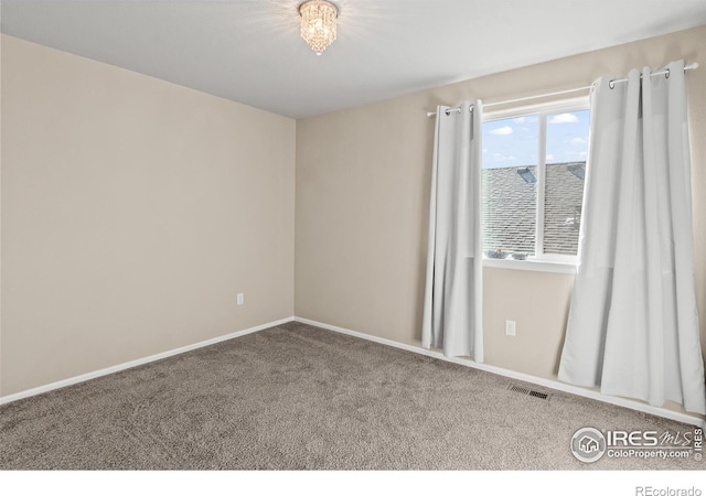 spare room featuring carpet, visible vents, and baseboards