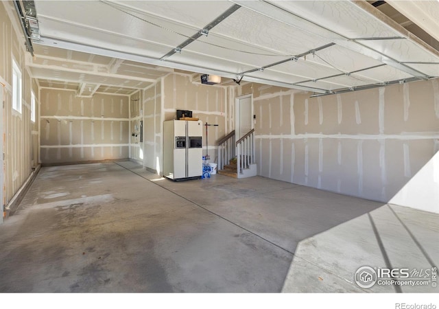 garage featuring white fridge with ice dispenser and a garage door opener