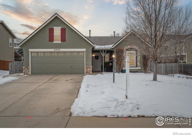 traditional-style home featuring stucco siding, concrete driveway, fence, a garage, and stone siding