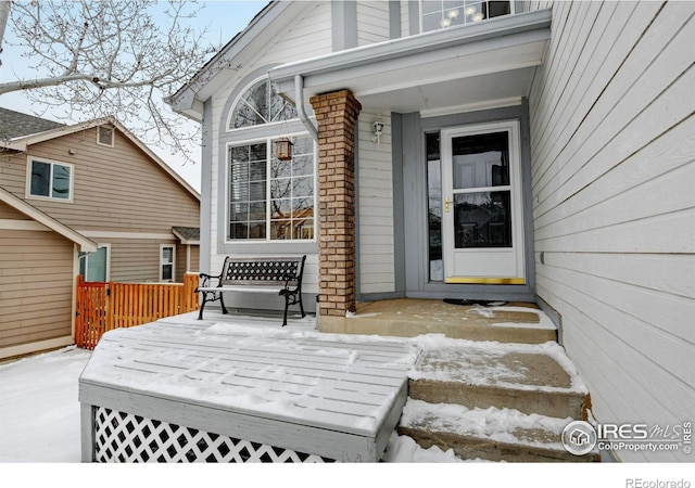 snow covered property entrance featuring a deck