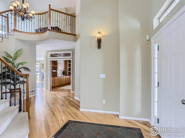 entrance foyer with an inviting chandelier, stairs, a high ceiling, and wood finished floors