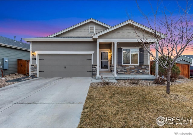 view of front of home with concrete driveway, an attached garage, covered porch, and stone siding