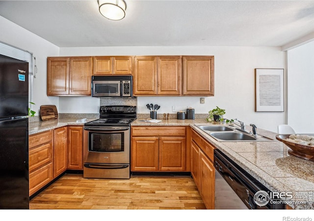 kitchen featuring appliances with stainless steel finishes, tile counters, brown cabinetry, and a sink