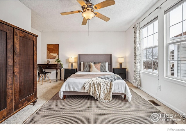 bedroom with light colored carpet, visible vents, a textured ceiling, and baseboards