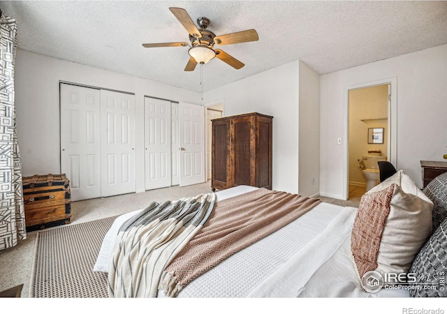 bedroom with a ceiling fan, light carpet, a textured ceiling, and two closets