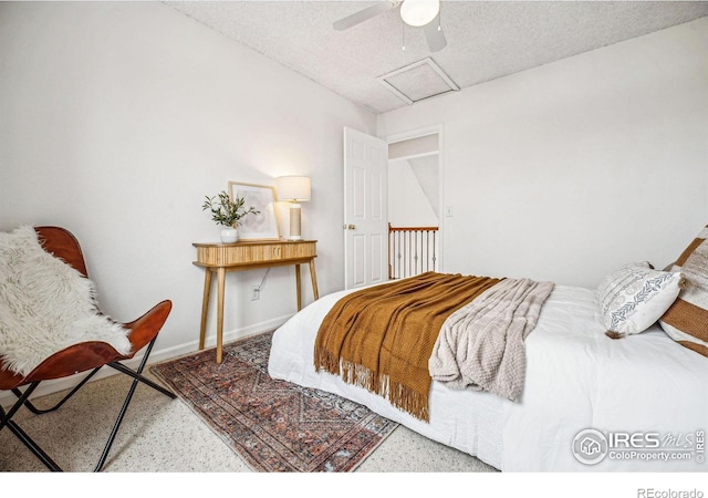 bedroom featuring a textured ceiling, a ceiling fan, attic access, and baseboards