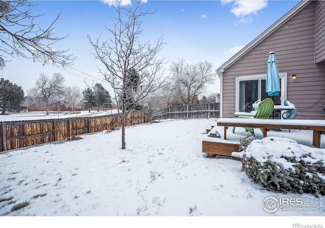 snowy yard featuring a fenced backyard