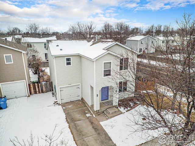 snow covered property featuring driveway and a garage