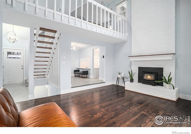 living room with a towering ceiling, baseboards, stairs, and wood finished floors