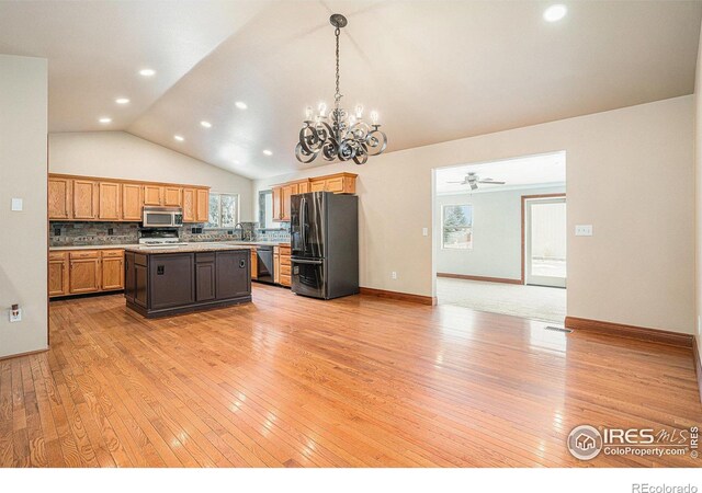 kitchen with a center island, tasteful backsplash, light countertops, black appliances, and decorative light fixtures