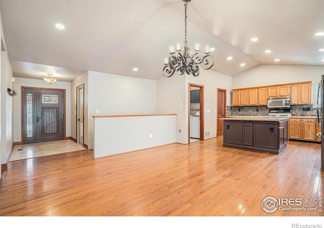 kitchen featuring light wood-style flooring, a kitchen island, stainless steel microwave, light countertops, and backsplash