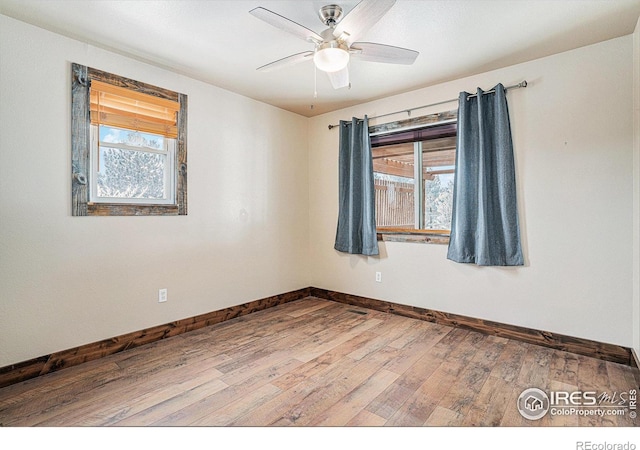 empty room featuring a ceiling fan, baseboards, and wood finished floors