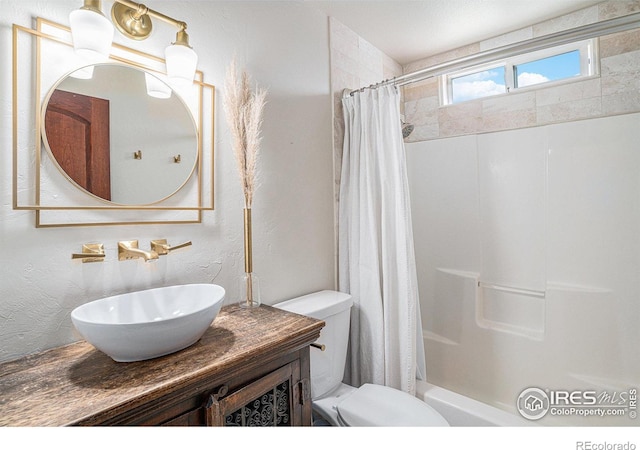 bathroom with shower / bath combo, toilet, vanity, and a textured wall