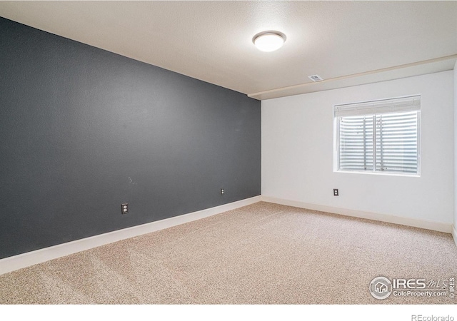 carpeted spare room with baseboards and visible vents