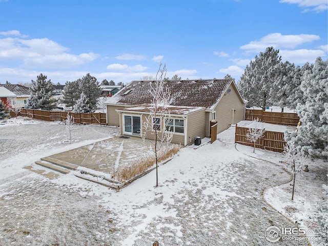 snow covered house featuring a fenced backyard