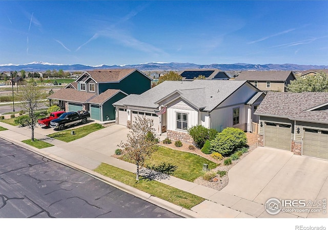 view of front of property featuring concrete driveway, a mountain view, an attached garage, and stone siding