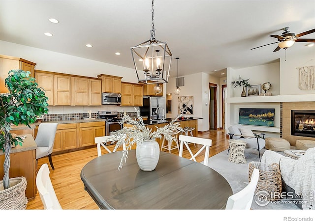 dining room featuring light wood-style flooring, recessed lighting, and ceiling fan with notable chandelier