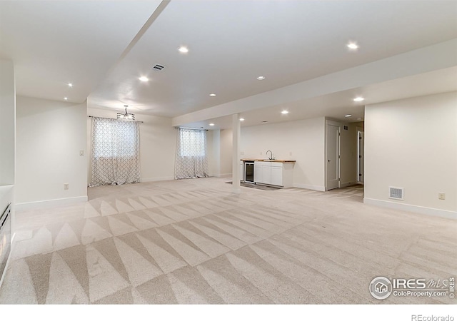 below grade area with recessed lighting, visible vents, a sink, wet bar, and light colored carpet