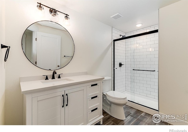 full bath featuring toilet, visible vents, wood finished floors, and a stall shower