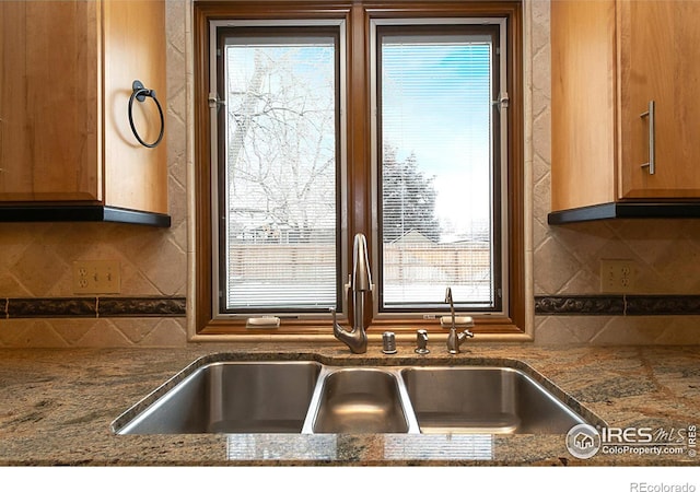 interior space featuring brown cabinetry, a sink, and backsplash