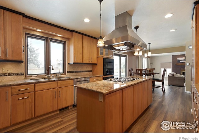 kitchen with decorative light fixtures, island exhaust hood, stainless steel appliances, a sink, and a kitchen island