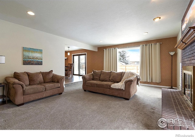 carpeted living area featuring a brick fireplace, a textured ceiling, and recessed lighting