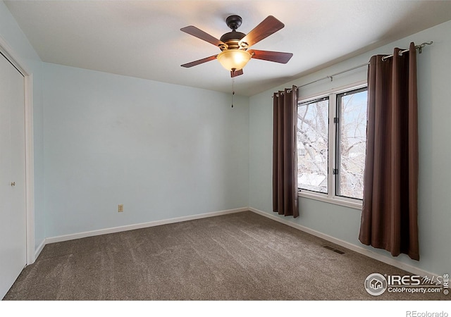 unfurnished room with carpet, visible vents, ceiling fan, and baseboards