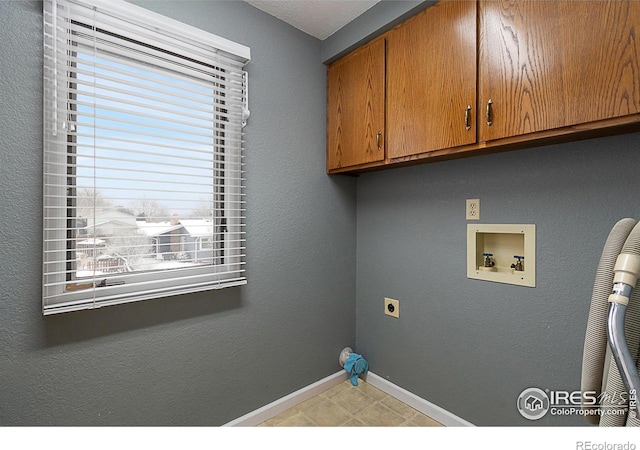 clothes washing area featuring cabinet space, baseboards, a textured wall, washer hookup, and electric dryer hookup