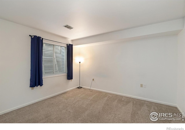 carpeted spare room featuring visible vents and baseboards