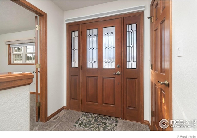 foyer featuring light carpet, visible vents, and baseboards