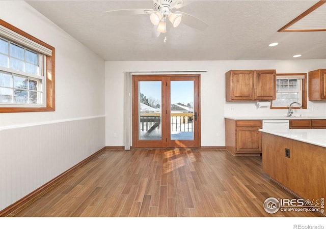 kitchen featuring brown cabinets, light wood-type flooring, light countertops, and a wealth of natural light