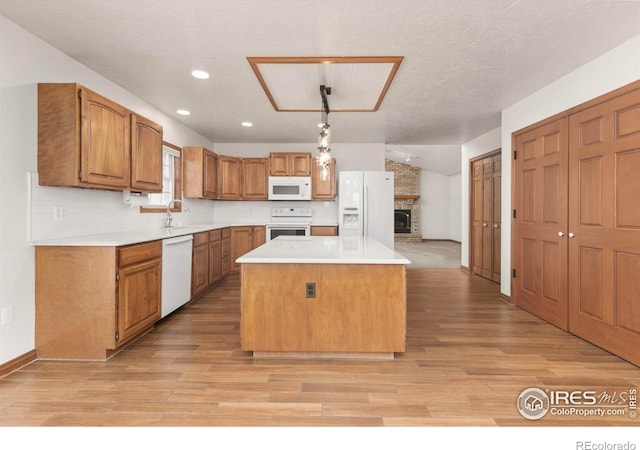 kitchen featuring light countertops, white appliances, brown cabinetry, and a kitchen island