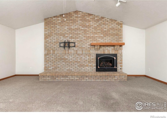 unfurnished living room featuring vaulted ceiling, a textured ceiling, carpet, and a fireplace