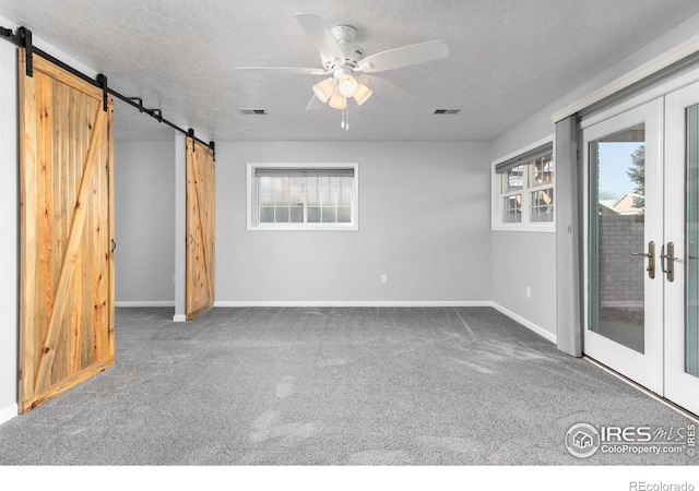 empty room featuring carpet, a barn door, visible vents, and french doors