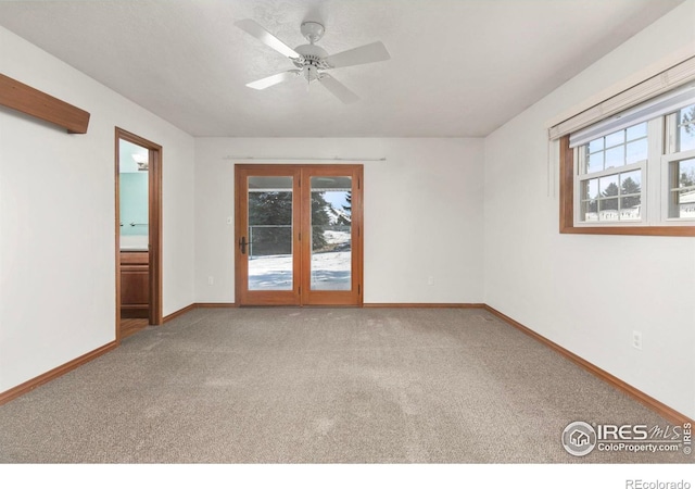 empty room featuring carpet, plenty of natural light, baseboards, and a ceiling fan