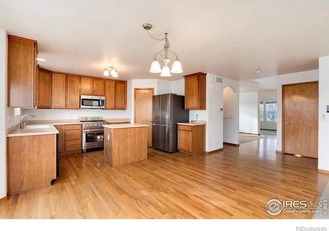 kitchen featuring brown cabinets, decorative light fixtures, a center island, stainless steel appliances, and light countertops