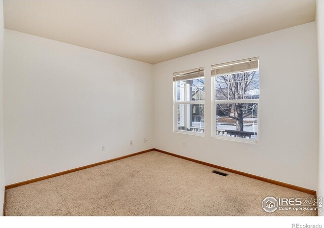 empty room featuring carpet floors, visible vents, and baseboards